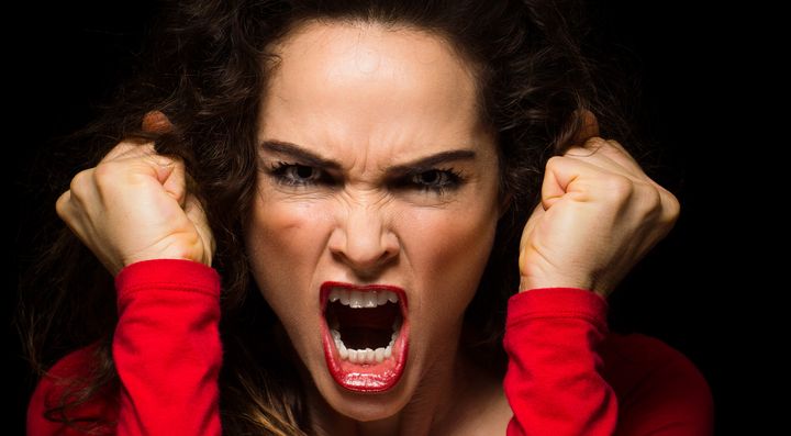  A very angry aggressive woman is clenching her fists in rage 